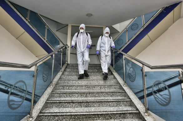 Two people in biological protective clothing go down a flight of stairs.